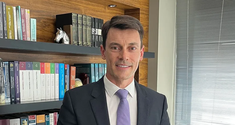 Dr. Paulo Roberto Martins no escritório, diante da biblioteca jurídica